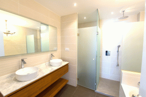 Cuarto de baño con dos lavabos sobrepuestos sobre mueble majo y ducha acristalada