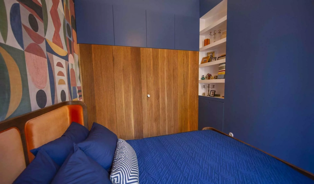 Dormitorio en azul con parte de una pared en madera con puerta integrada 