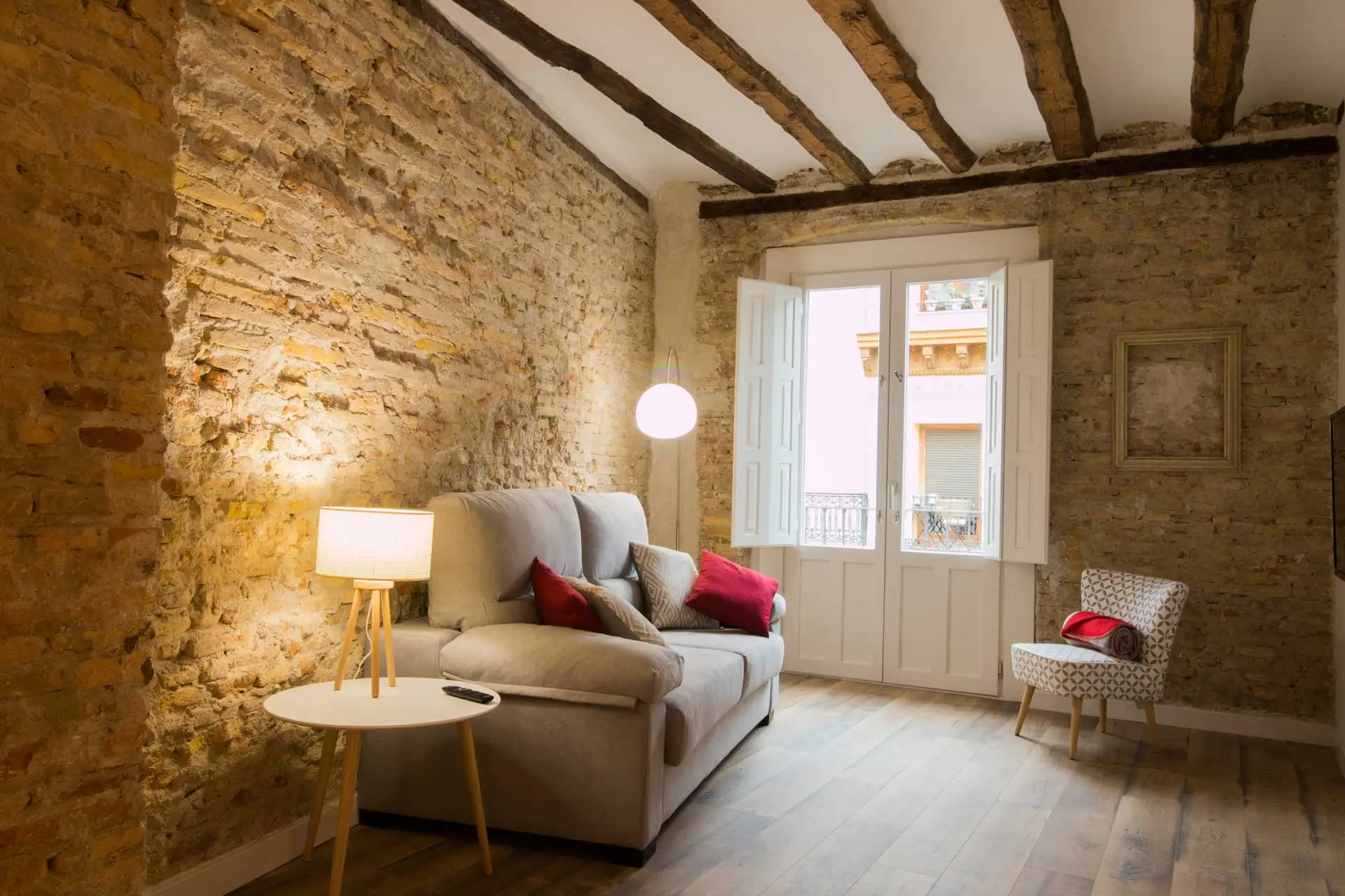 Reforma en Madrid de apartamento con salón con paredes en bruto y vigas originales vistas