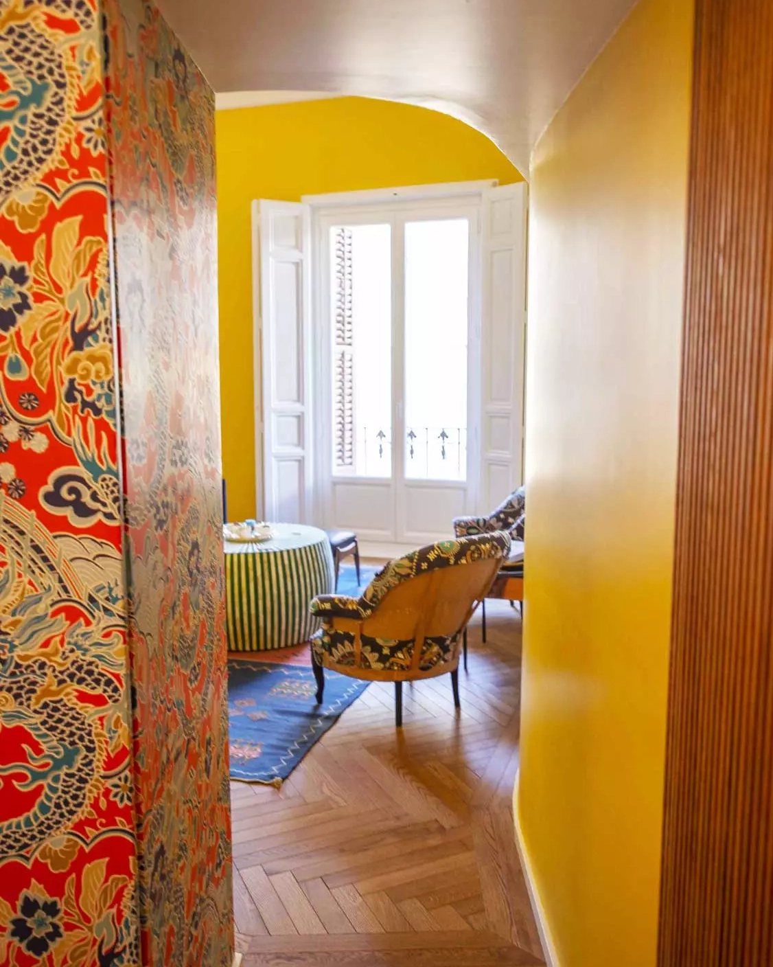 Pasillo semiabovedado | 5 distribuciones para pisos de 90 m² Pasillo de entrada a salón semiabovedada con decoración boho chic y colores llamativos en Embajadores, Madrid.