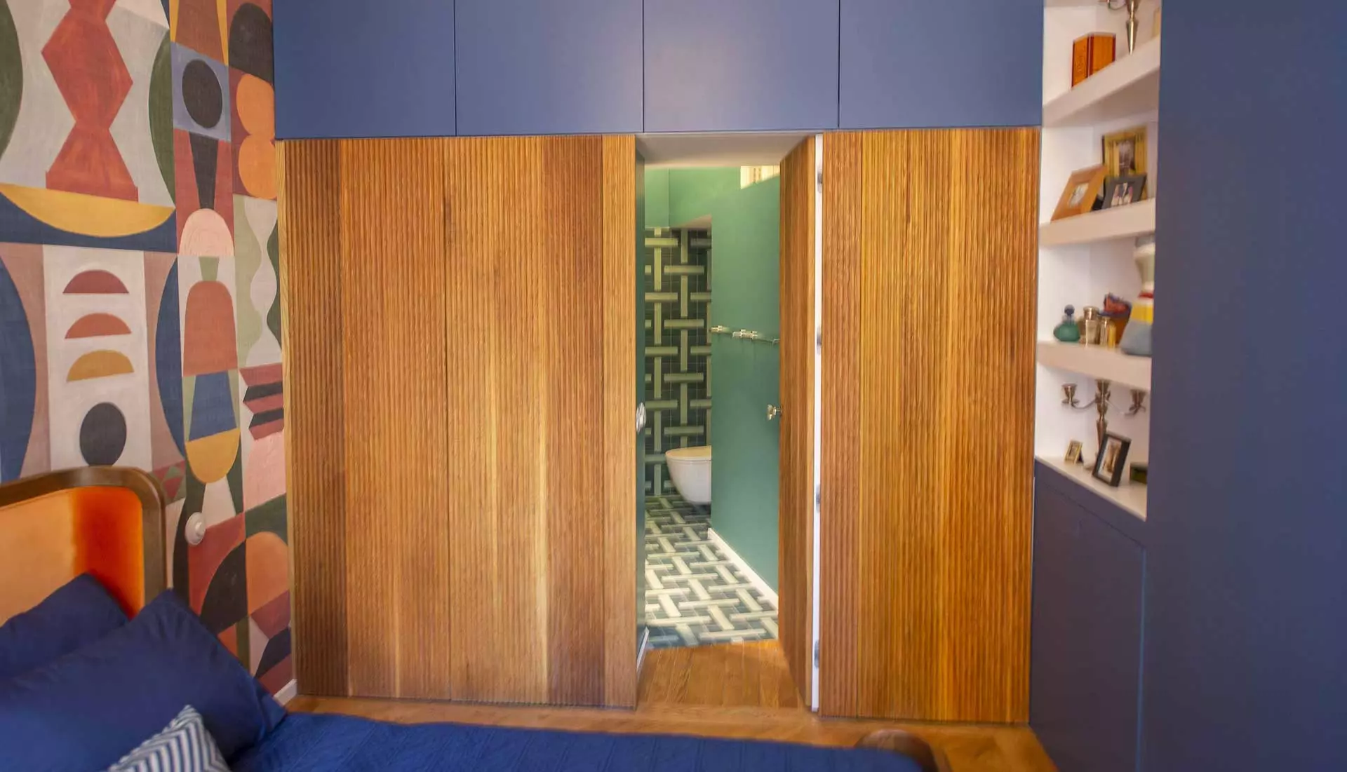 Pared de dormitorio en madera con puerta integrada abierta al baño de la habitación