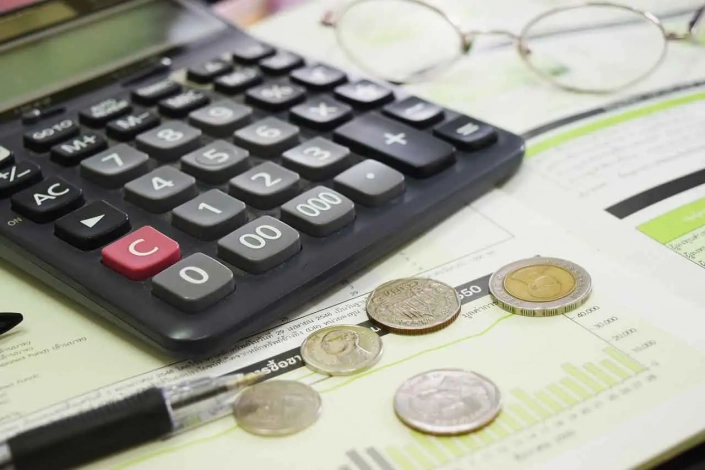 Una calculadora, unas monedas de euros y un bolígrafo sobre documentación de reformas en Madrid