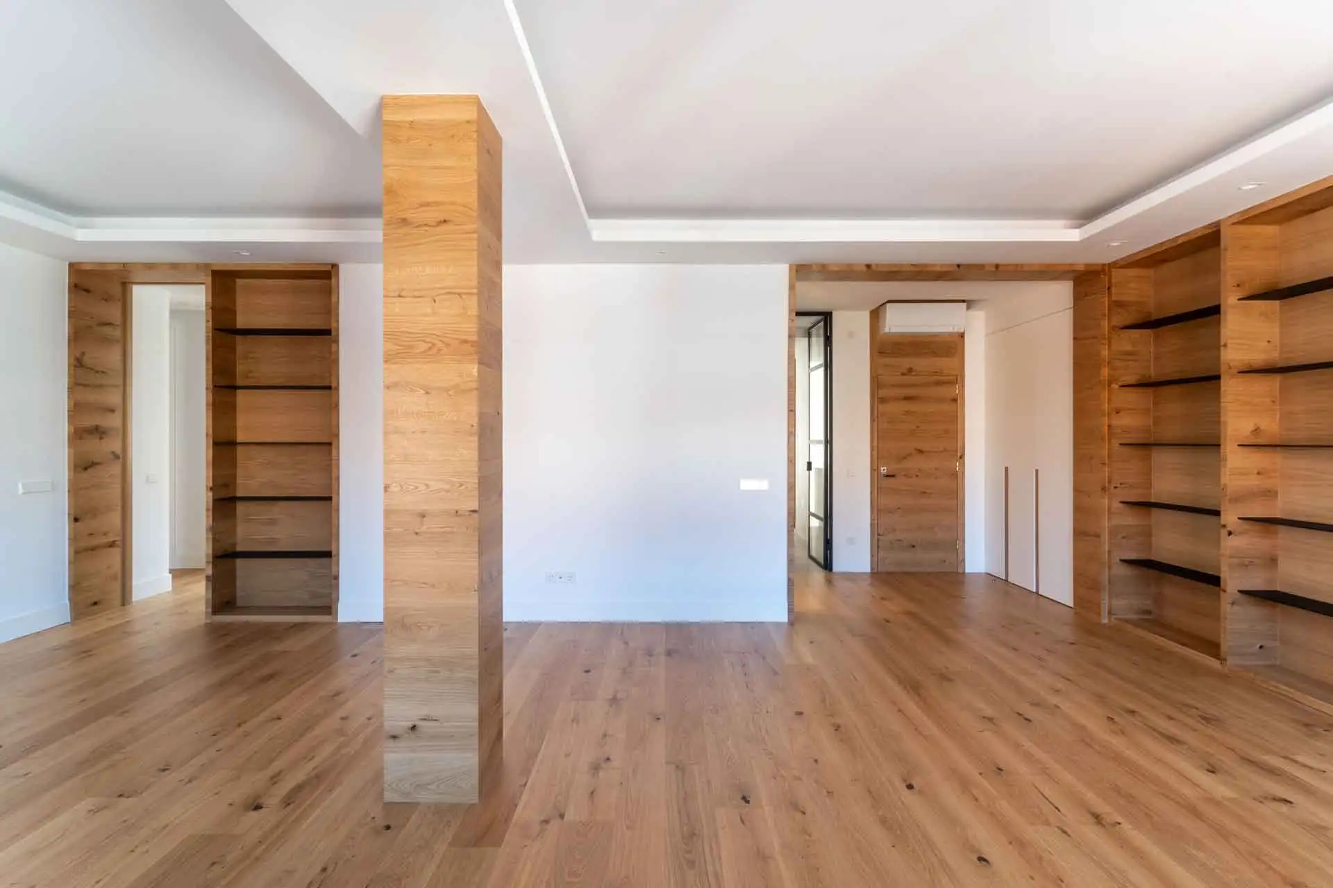 Salón de piso en Madrid, calle Menéndez Pelayo, con viga forrada de madera y estantería empotrada de madera