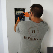 Un electricista de la empresa de reformas en Madrid Honrados, con guantes de seguridad, trabaja en el cuadro de luces para cambiar la instalación eléctrica de una vivienda.