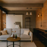 interior de una vivienda que anteriormente fue un local comercial en Madrid. Decorada con un estilo industrial, la imagen destaca las paredes de ladrillo visto, elementos metálicos y una decoración que refleja su pasado comercial pero adaptada a su nuevo uso residencial