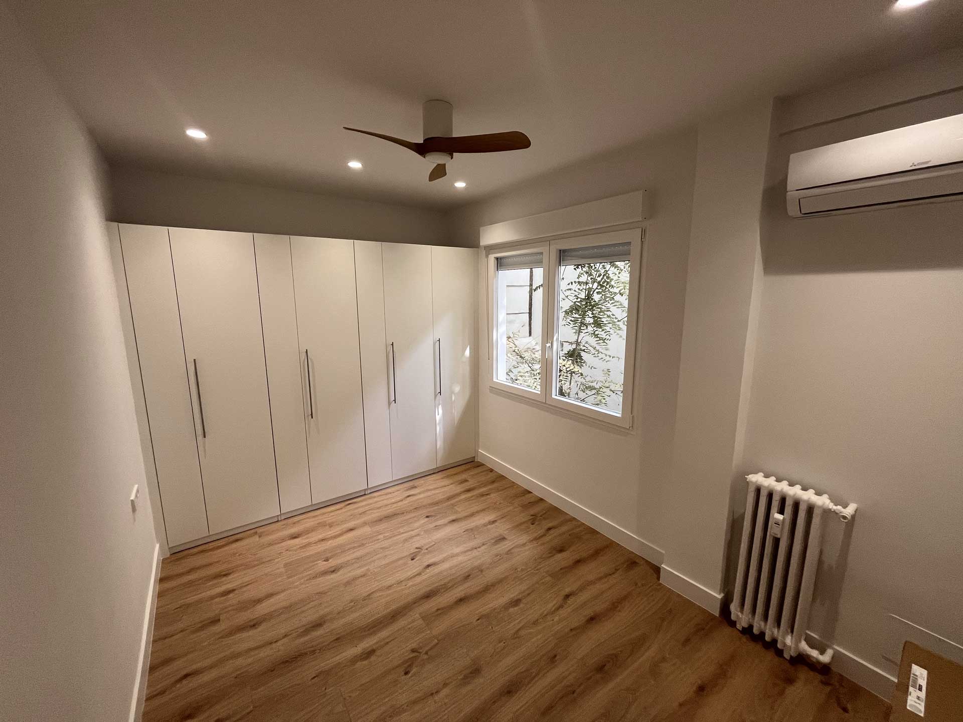 Dormitorio principal en Tirso de Molina, con armarios de Ikea de pared a pared, suelo laminado y ventilador en el techo.