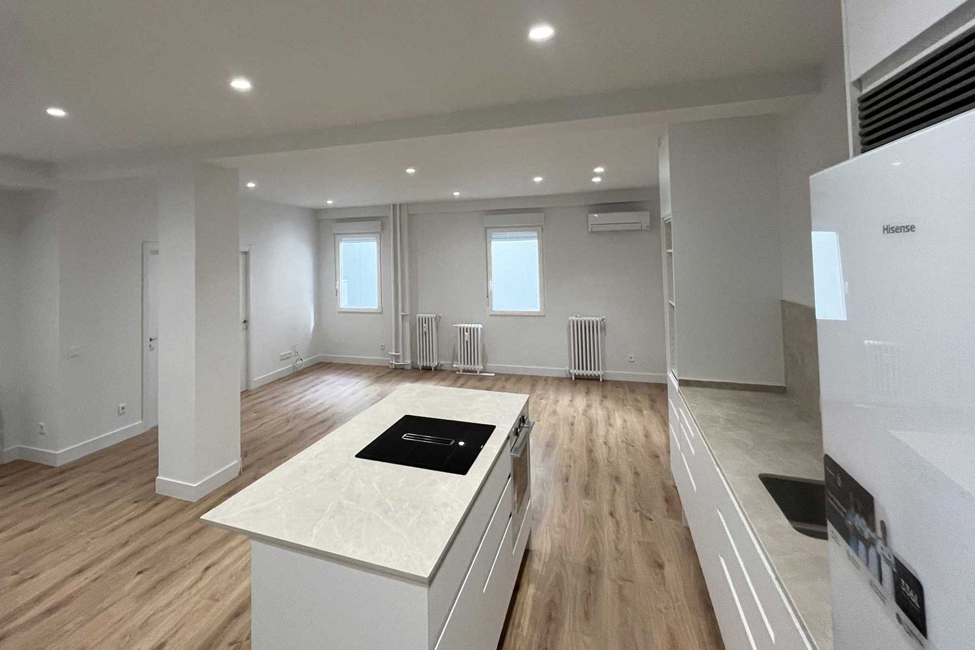 Amplio salón con cocina americana en vivienda de la calle Tirso de Molina después de la reforma integral realizada por una de las mejores empresas de reformas en Madrid