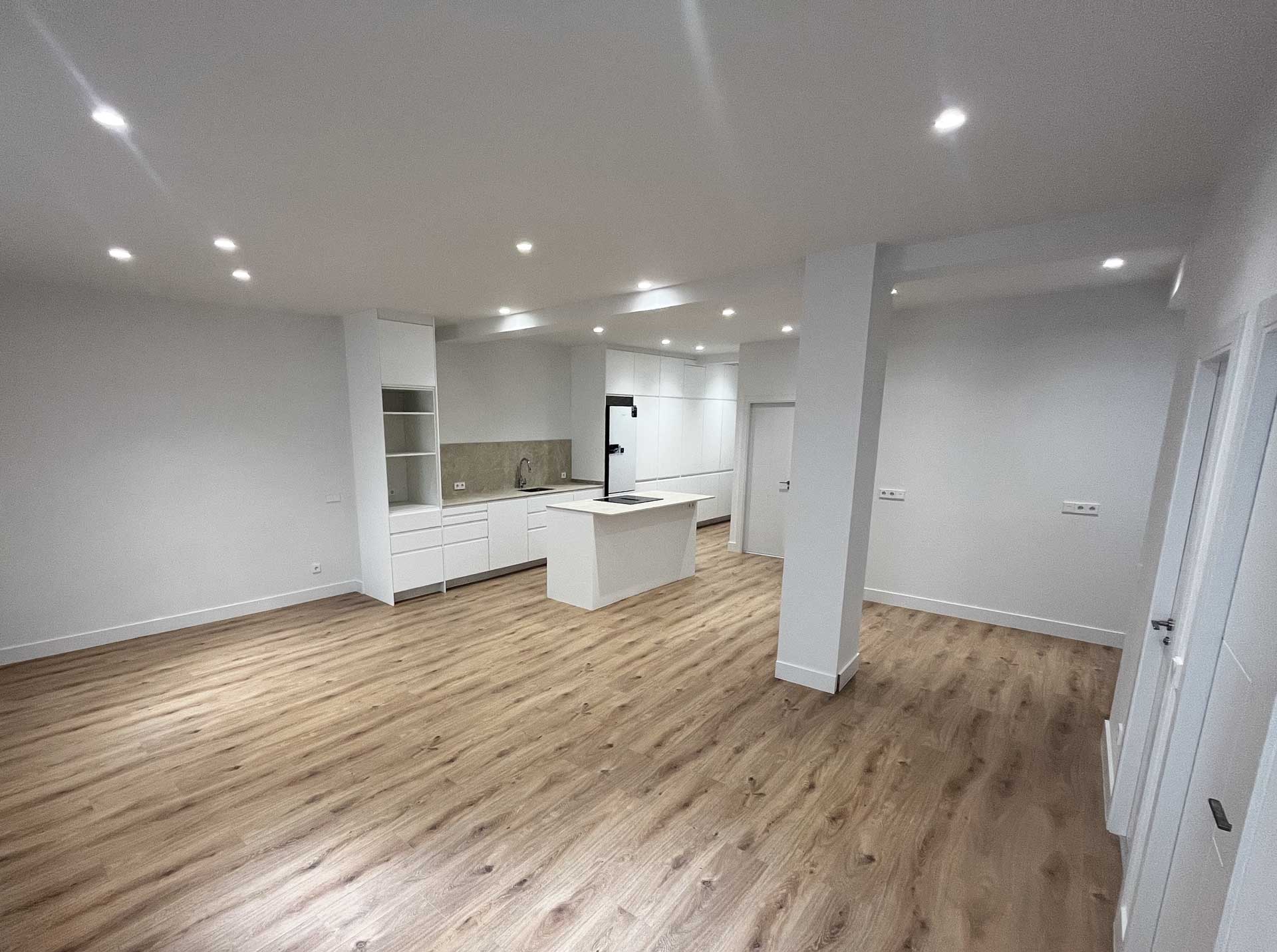 Amplio y luminoso salón y cocina americana en vivienda de Tirso de Molina después de la reforma integral realizada por la empresa de reformas en Madrid Honrados