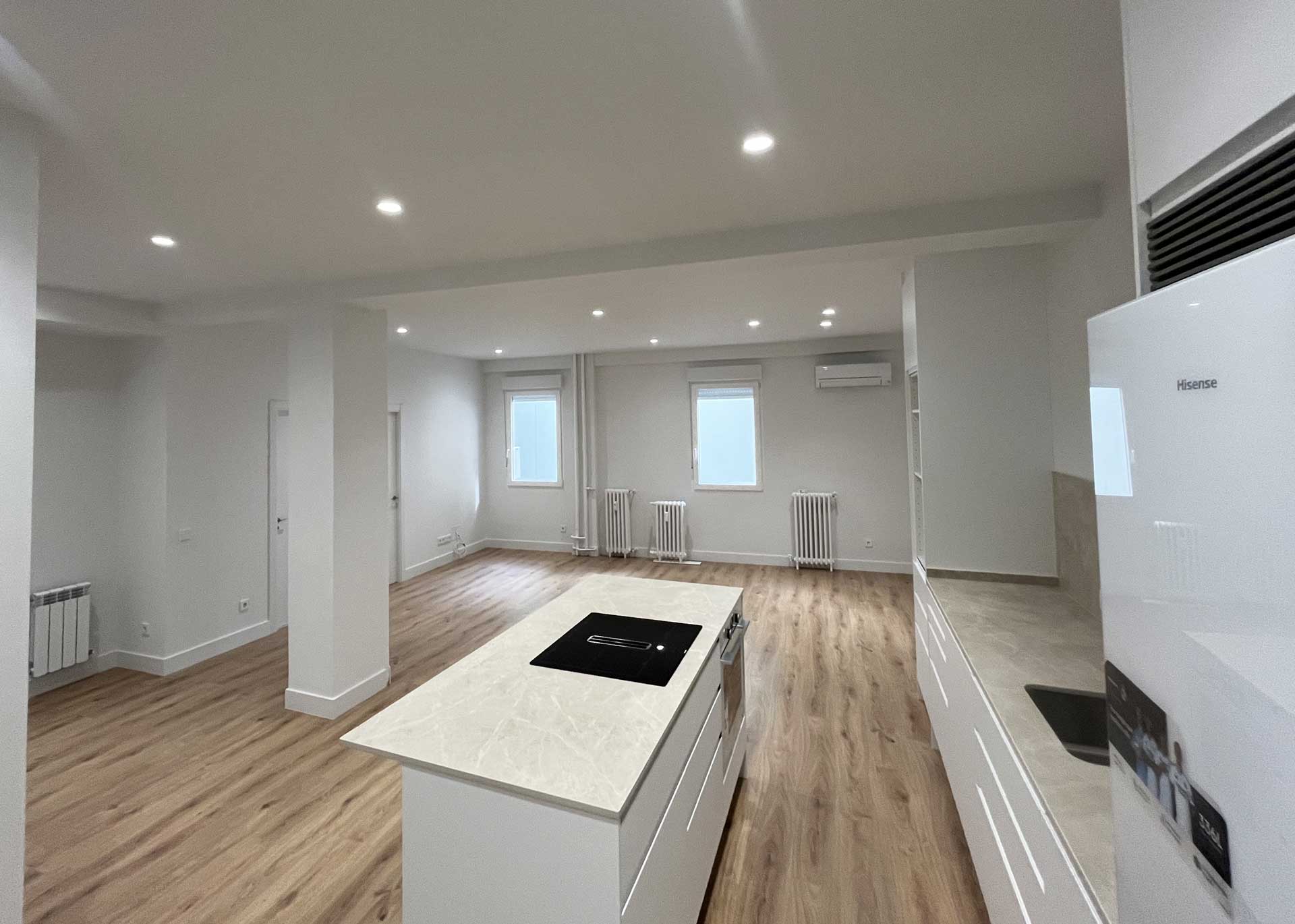 Salón y cocina abierta con isla e iluminación técnica tras reforma integral en Tirso de Molina