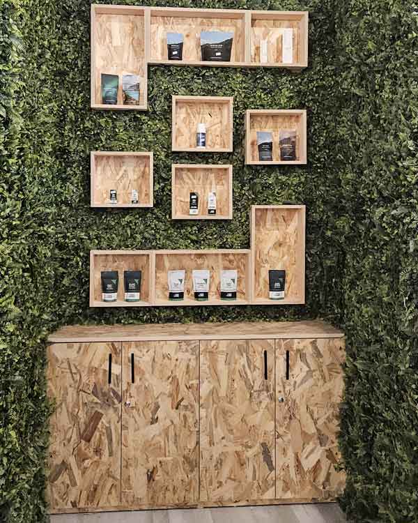 zona de infusiones de la tienda cultura cannábica en Malasaña después de la reforma con pared de césped artificial Y estantes con madera de OSB