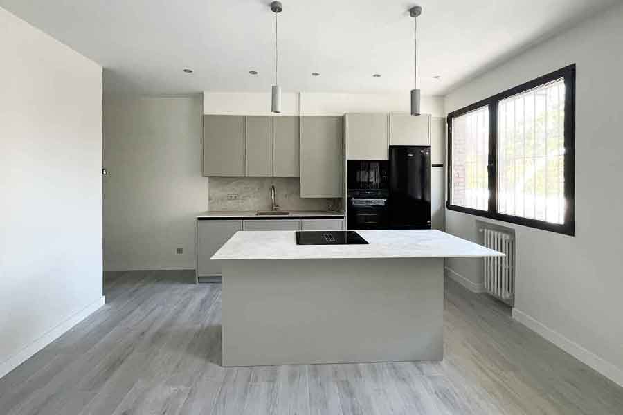 ofina-convertida-vivienda-madrid primer plano de cocina americana con isla, con zona de cocción y campana extractora integrada de una oficina en Madrid convertida en dos viviendas
